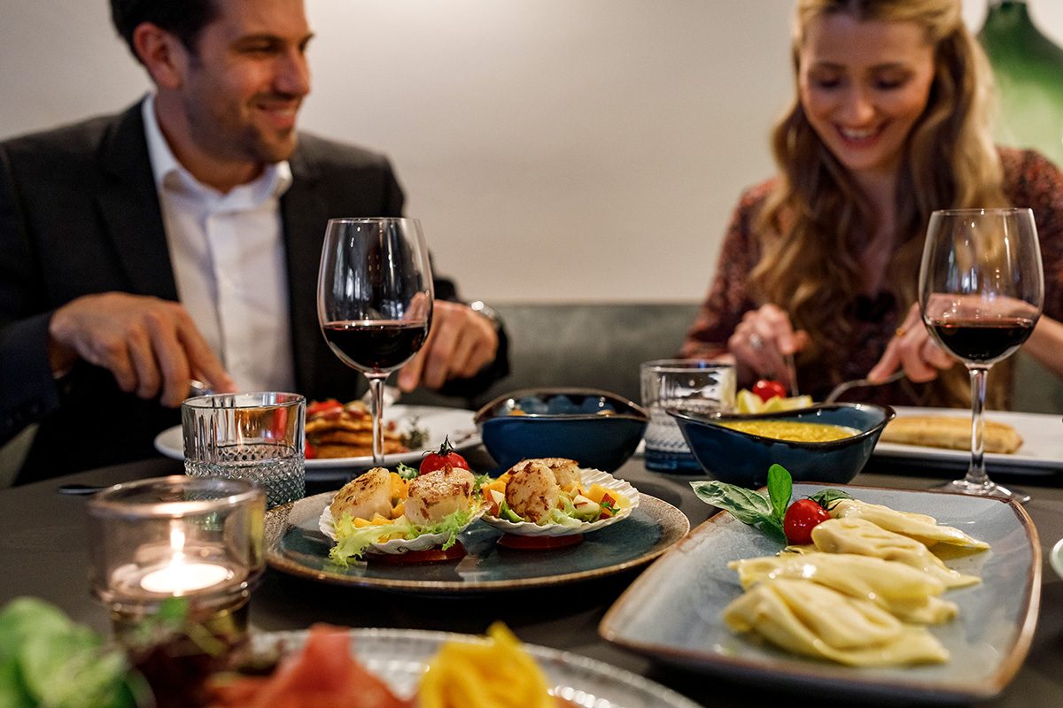 Mann und Frau sitzen beim Essen und probieren italienische Gerichte