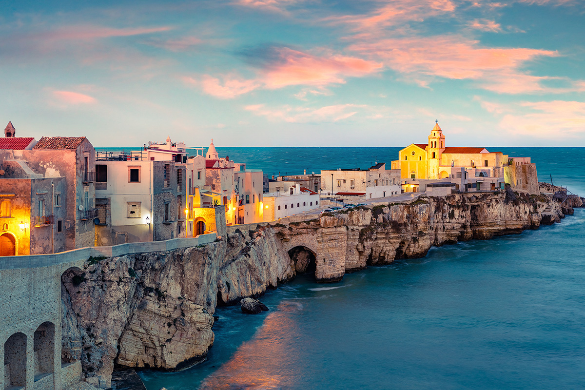 Eine italienische Stadt am Meer mit Abendrot im Hintergrund
